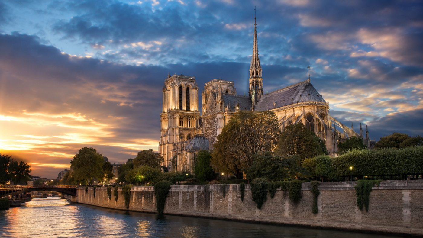 The restored Notre-Dame de Paris cathedral with its rebuilt spire and clean pale stone glowing under a dramatic evening sky