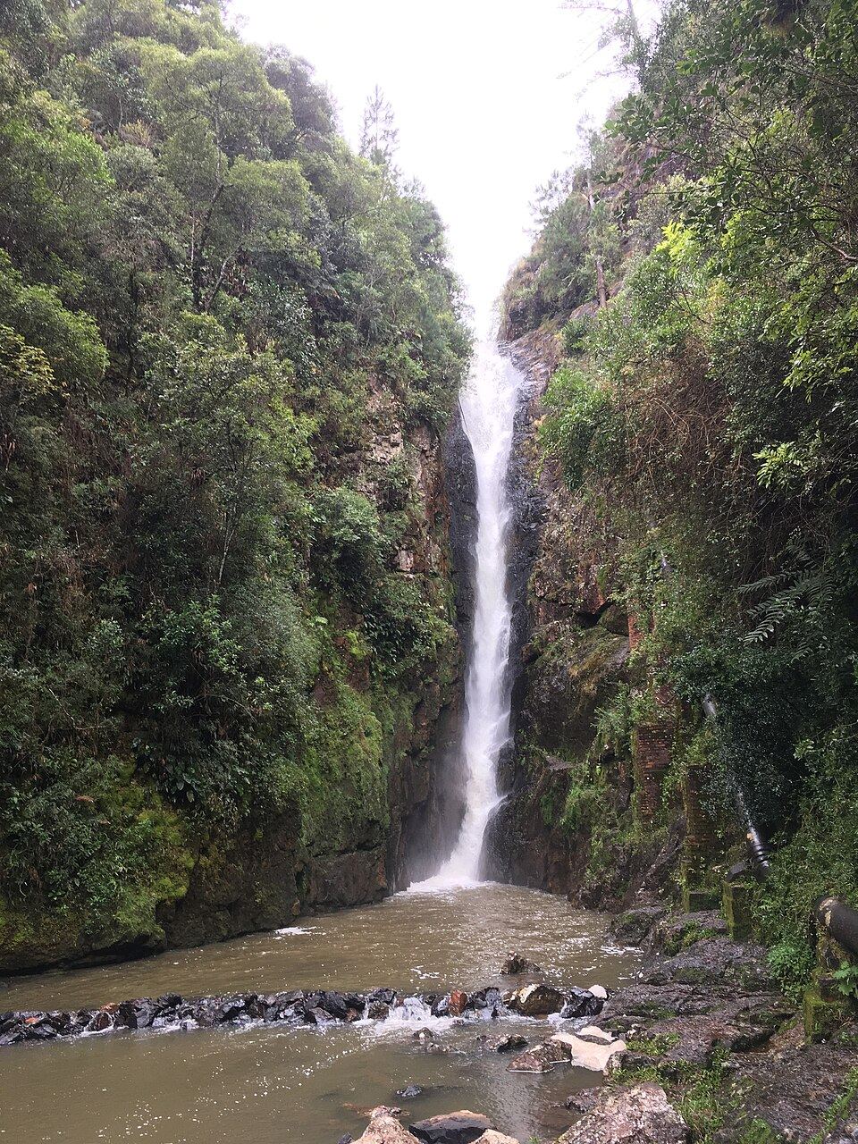Queda d’água da Cascata Paraíso entre paredões cobertos de vegetação, em fotografia de 2017.