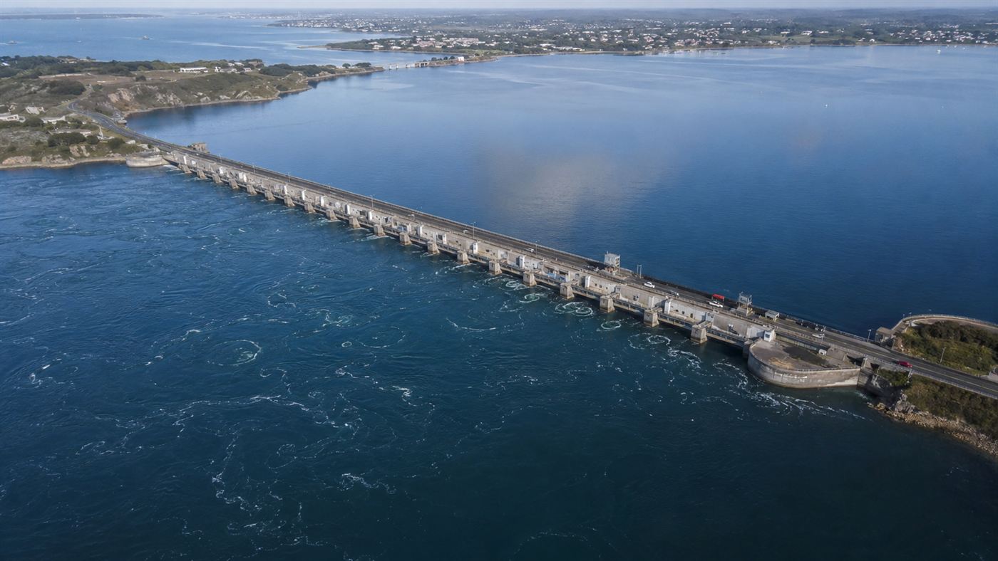 The long La Rance tidal barrage stretching across a wide estuary in Brittany with water on both sides and a road on top