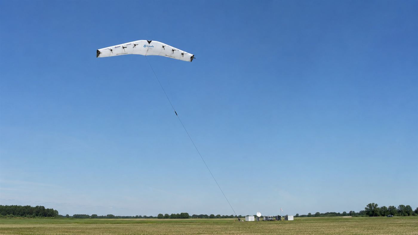 A rigid winged Makani energy kite with rotors along the wing flying high in the sky on a long tether