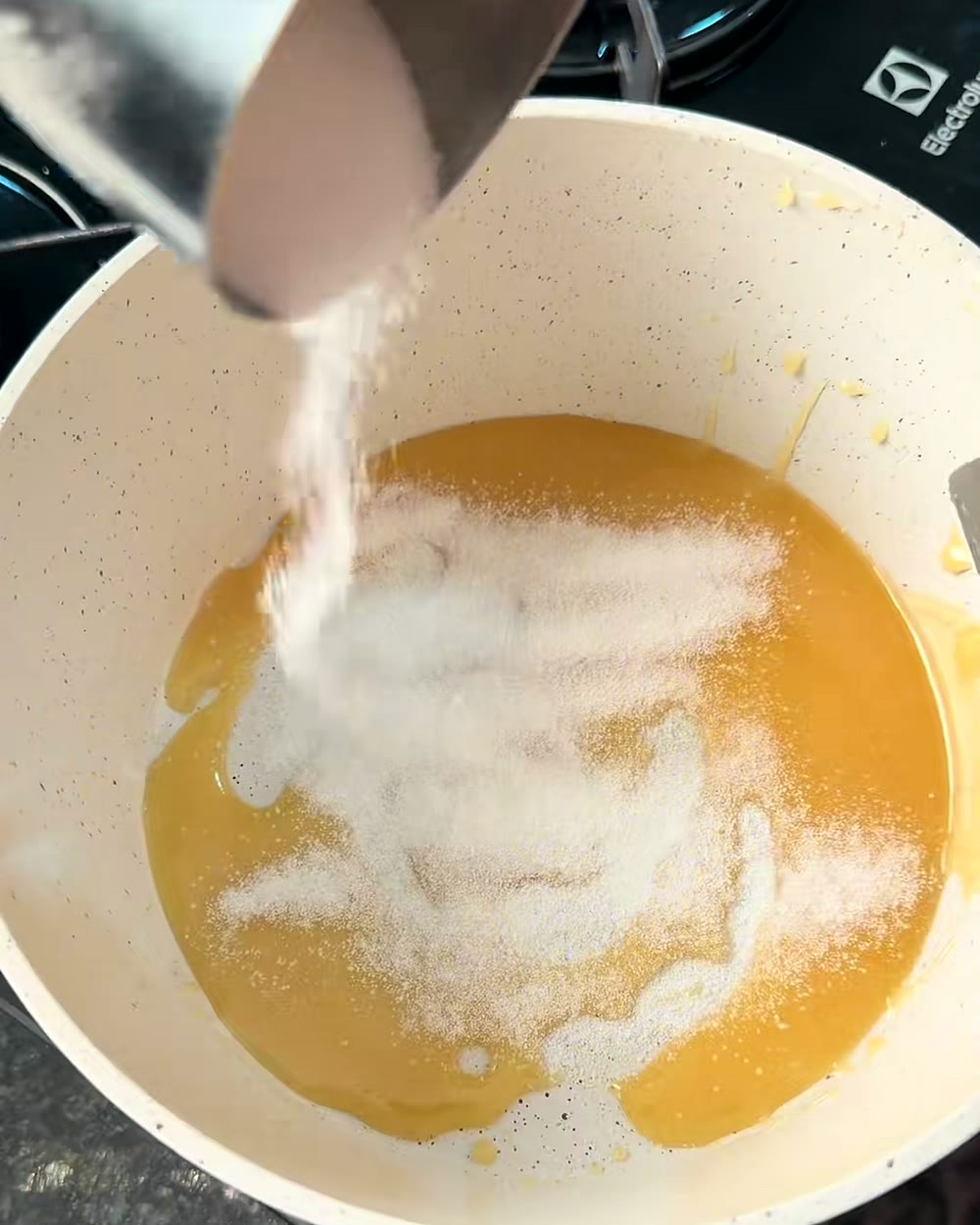 Cobertura de chocolate branco cravejada de caramelo vermelho sendo preparada, frame do vídeo viral