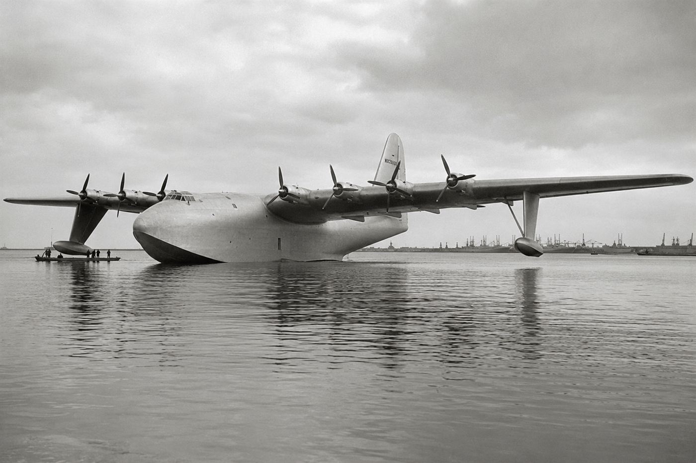 The Spruce Goose H-4 Hercules flying boat built by Howard Hughes floating on Long Beach harbor in 1947, the massive wooden aircraft with eight propeller engines reflecting in the calm water