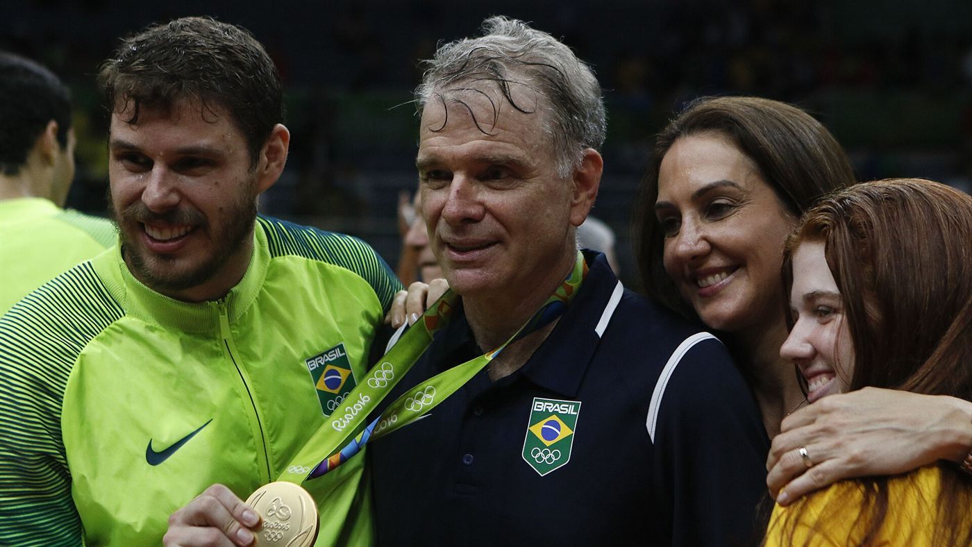 Jogador e técnico da seleção brasileira de vôlei comemoram um título com medalha em torneio internacional