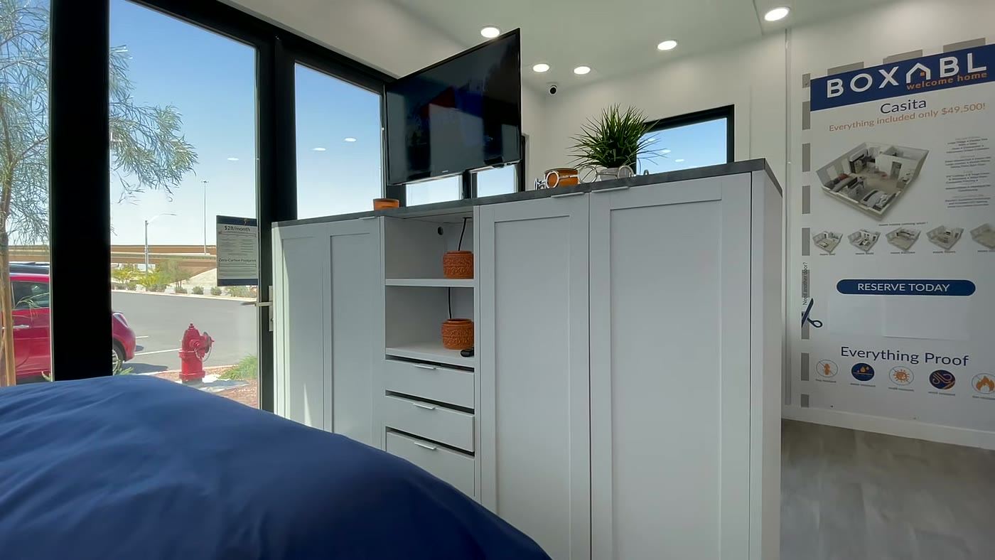Interior da casa dobrável Boxabl Casita com quarto, armário e televisão