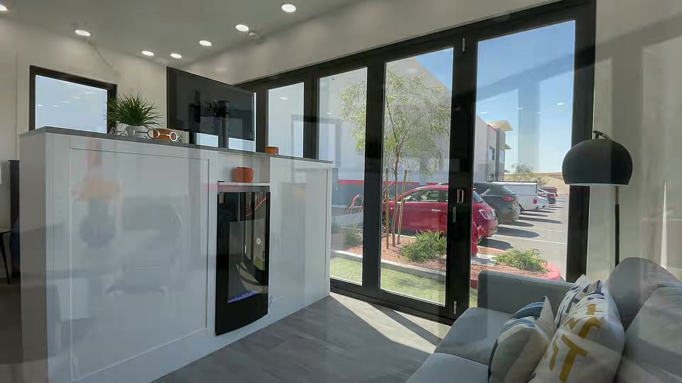 Sala de estar da casa dobrável Boxabl Casita com sofá, lareira elétrica e janelas de vidro