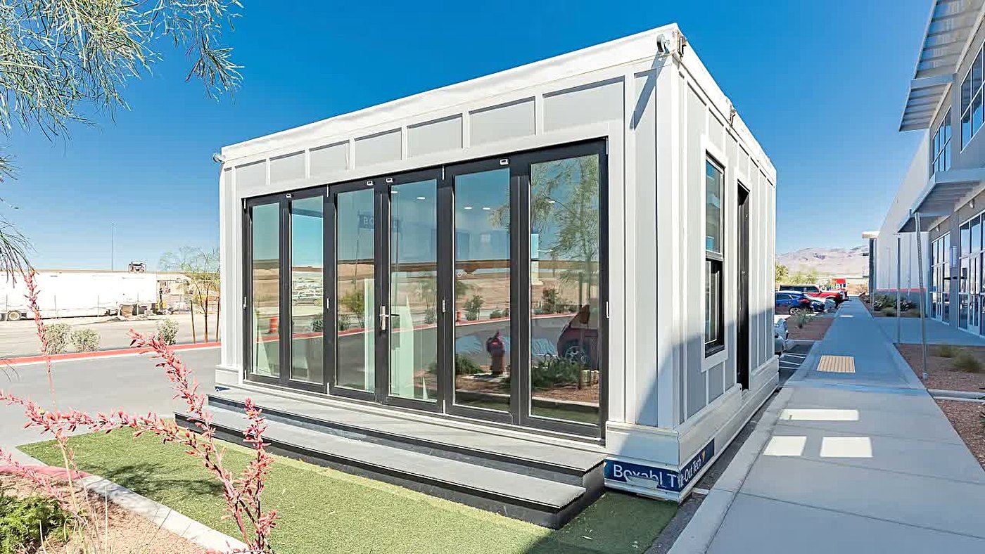 Casa dobrável Boxabl Casita já montada em um terreno, com fachada de vidro e estrutura branca