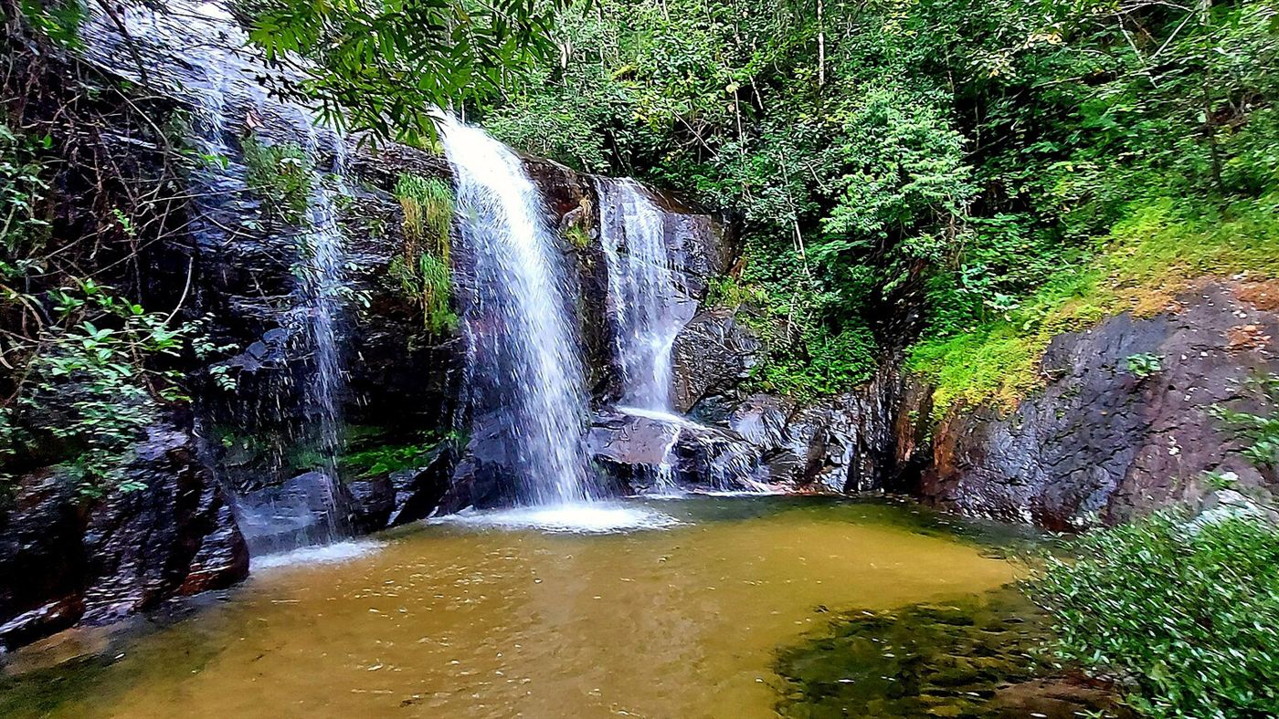 Cachoeira em meio à mata fechada, com poço natural na base, cenário típico das quedas d'água do interior do Tocantins