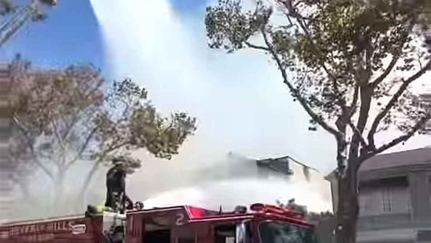 Caminhão de bombeiros joga água sobre a fumaça na casa de Erik Marmo em Los Angeles