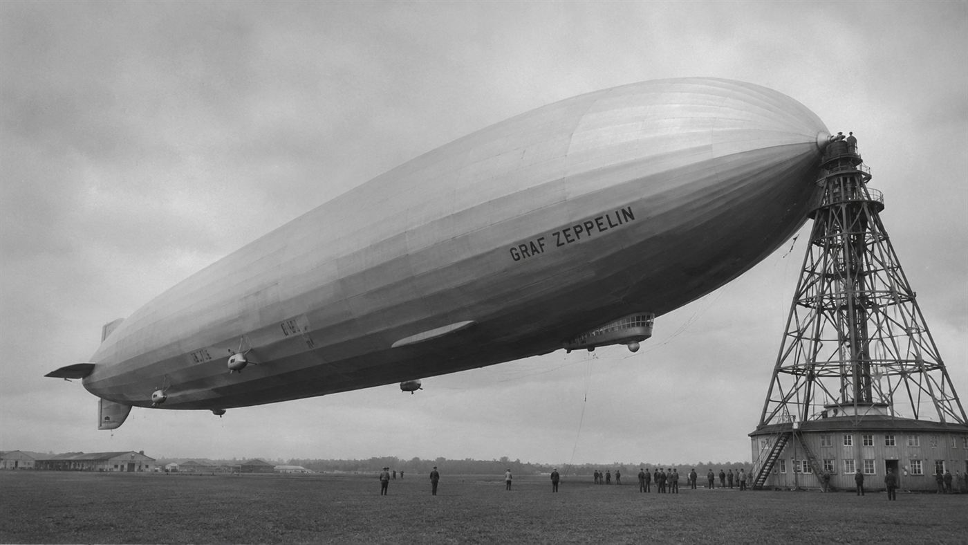 The huge silver British R101 airship moored to its tall mast above the airfield at Cardington in 1930