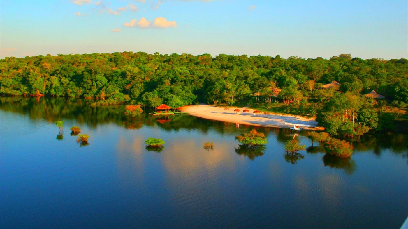 Faixa de areia exposta às margens de um rio de água escura perto de Manaus