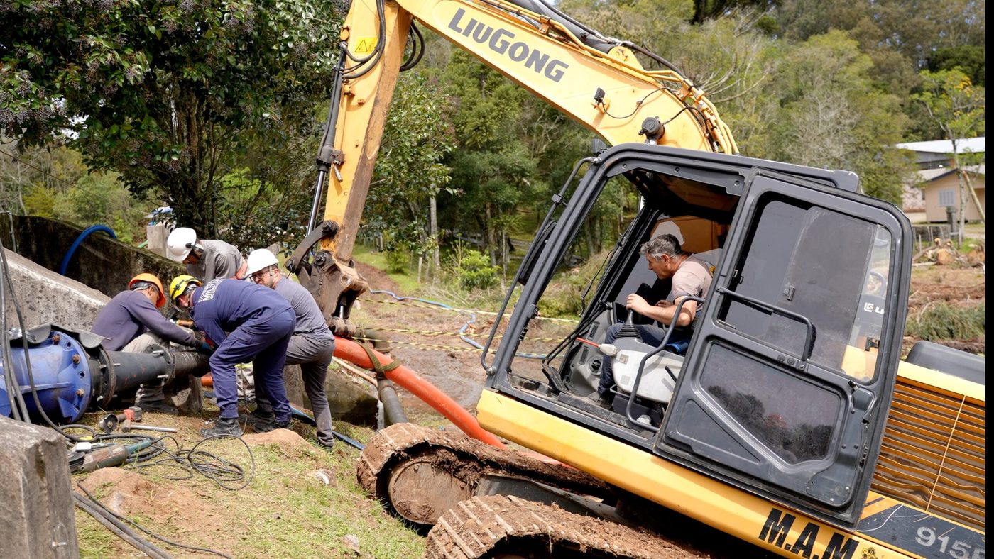 Técnicos e bombeiros instalam bomba e mangueiras ao lado da Barragem Arroio São Luiz, em São Marcos, com uma escavadeira