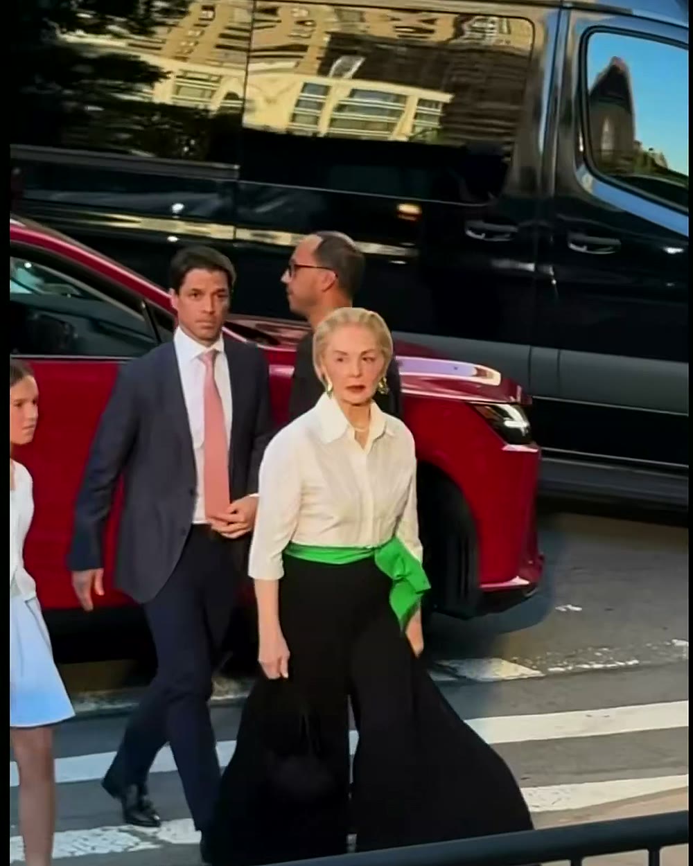 Carolina Herrera atravessa a rua a caminho do desfile cercada pela equipe
