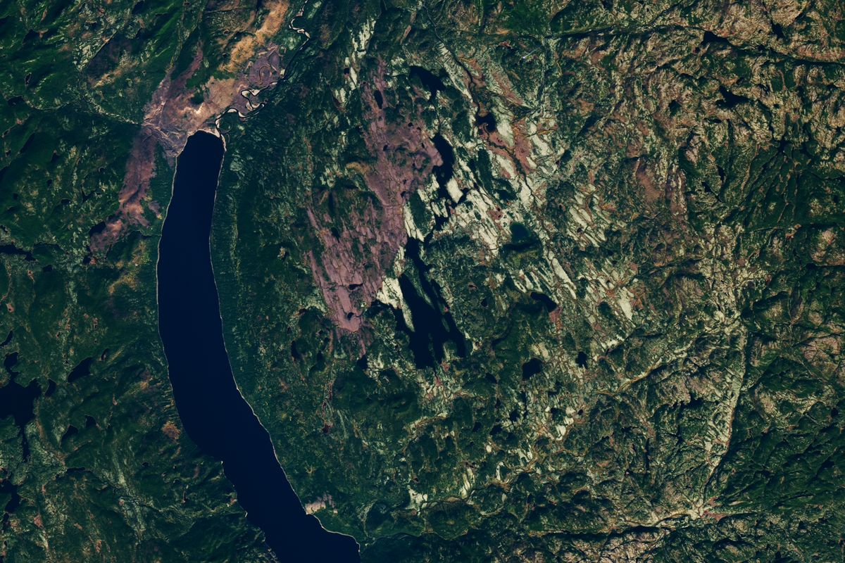 Detalhe da imagem de satélite com rochas claras, floresta e pequenos lagos na área da estrutura de Uhackatik, ao lado de um lago comprido