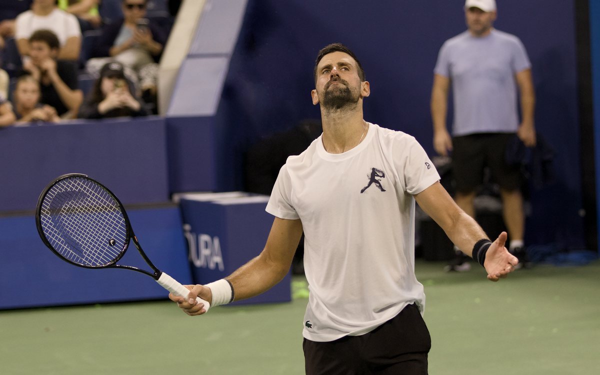 Novak Djokovic abre os braços e olha para cima durante treino aberto na Arthur Ashe, em agosto de 2026