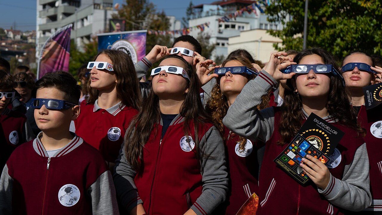Estudantes usam óculos certificados para observar um eclipse solar com segurança em evento público
