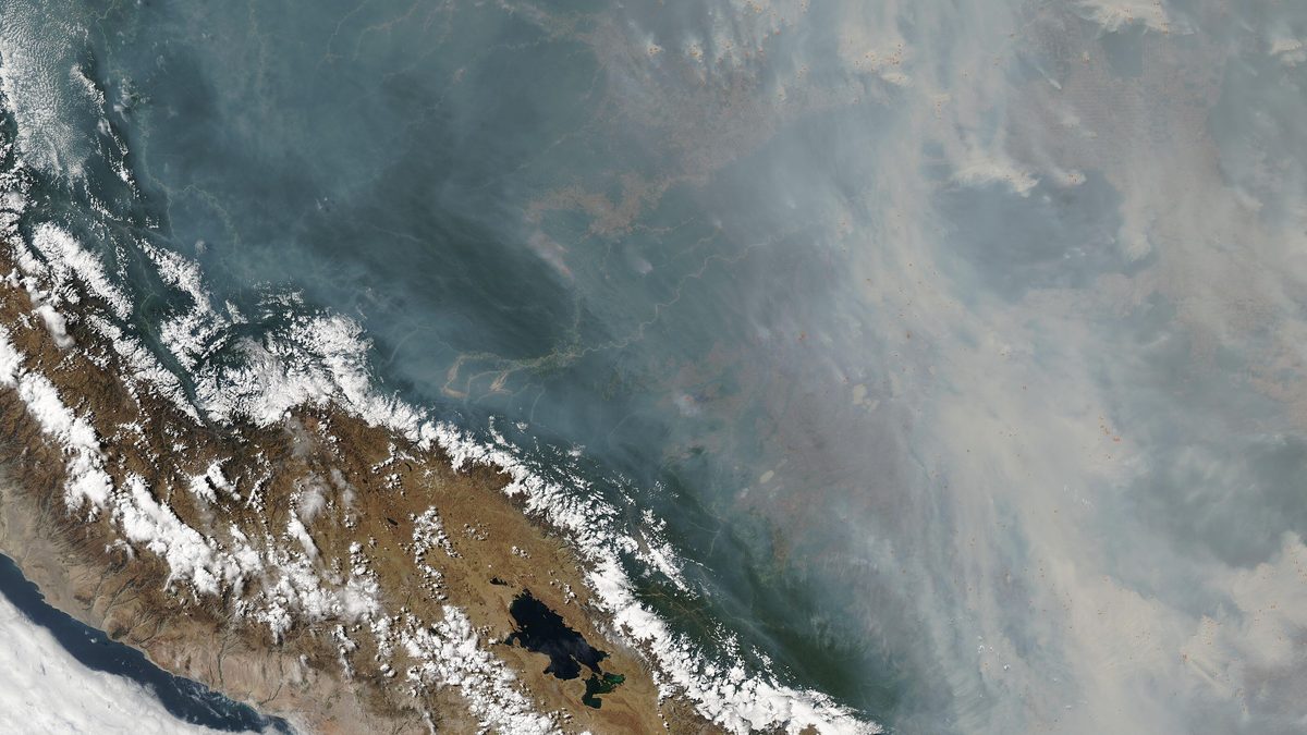 Imagem de satélite com névoa cinza de fumaça cobrindo a Bolívia e o oeste do Brasil, a leste da Cordilheira dos Andes