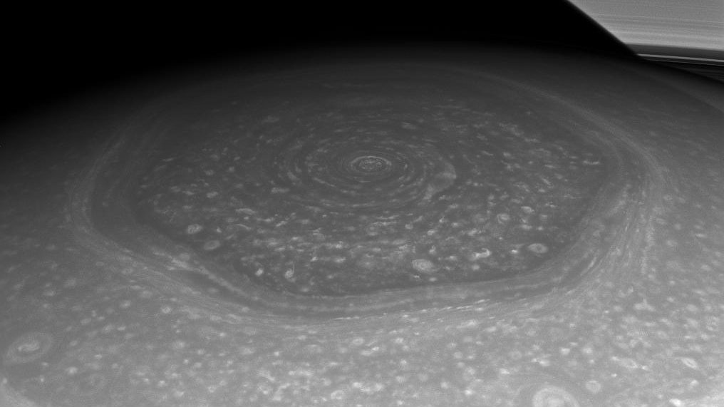 O hexágono do polo norte de Saturno visto de lado pela sonda Cassini, com um trecho dos anéis no canto