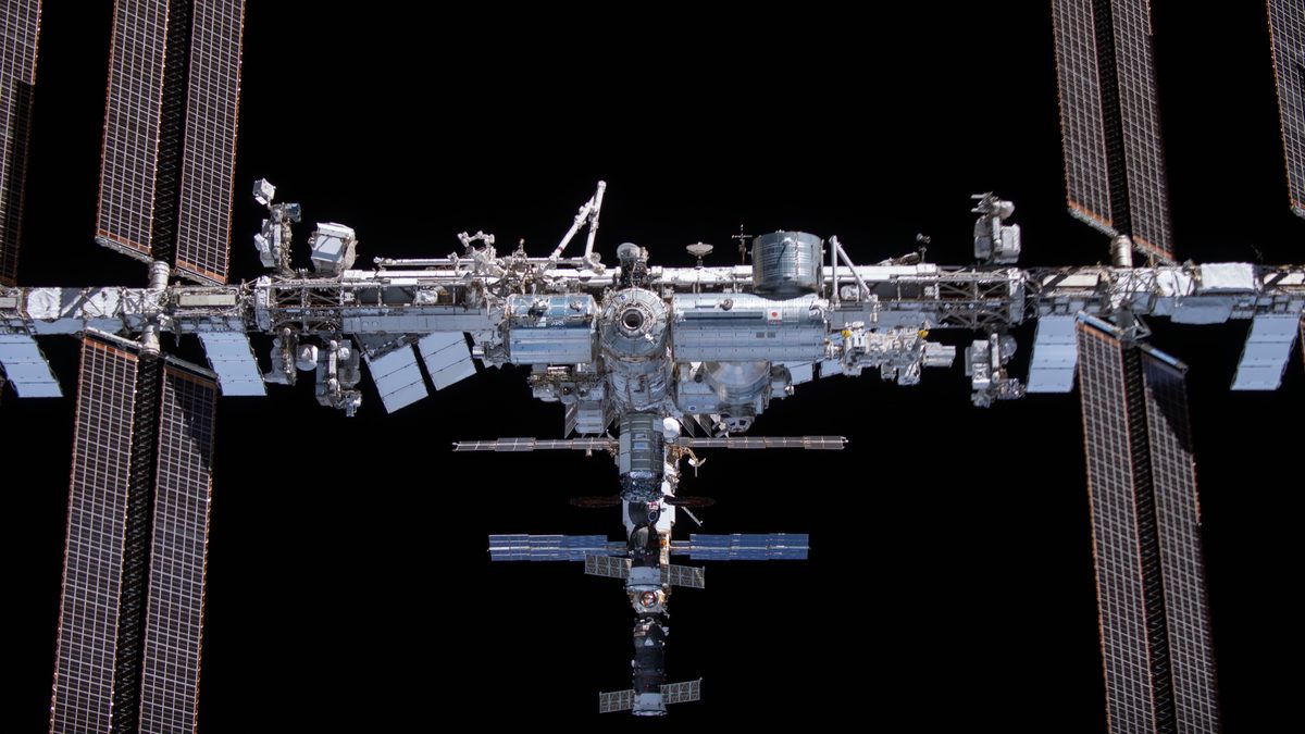 Estação Espacial Internacional vista de frente, com painéis solares escuros nas laterais, fotografada da cápsula Crew Dragon Endeavour