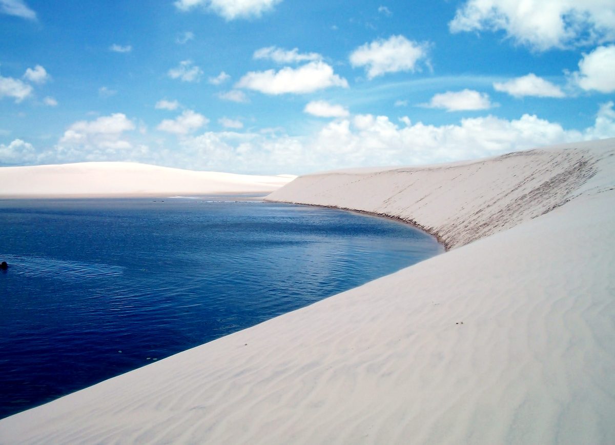 Lagoa azul profunda encostada em duna de areia branca no Parque Nacional dos Lençóis Maranhenses, perto de São Luís.