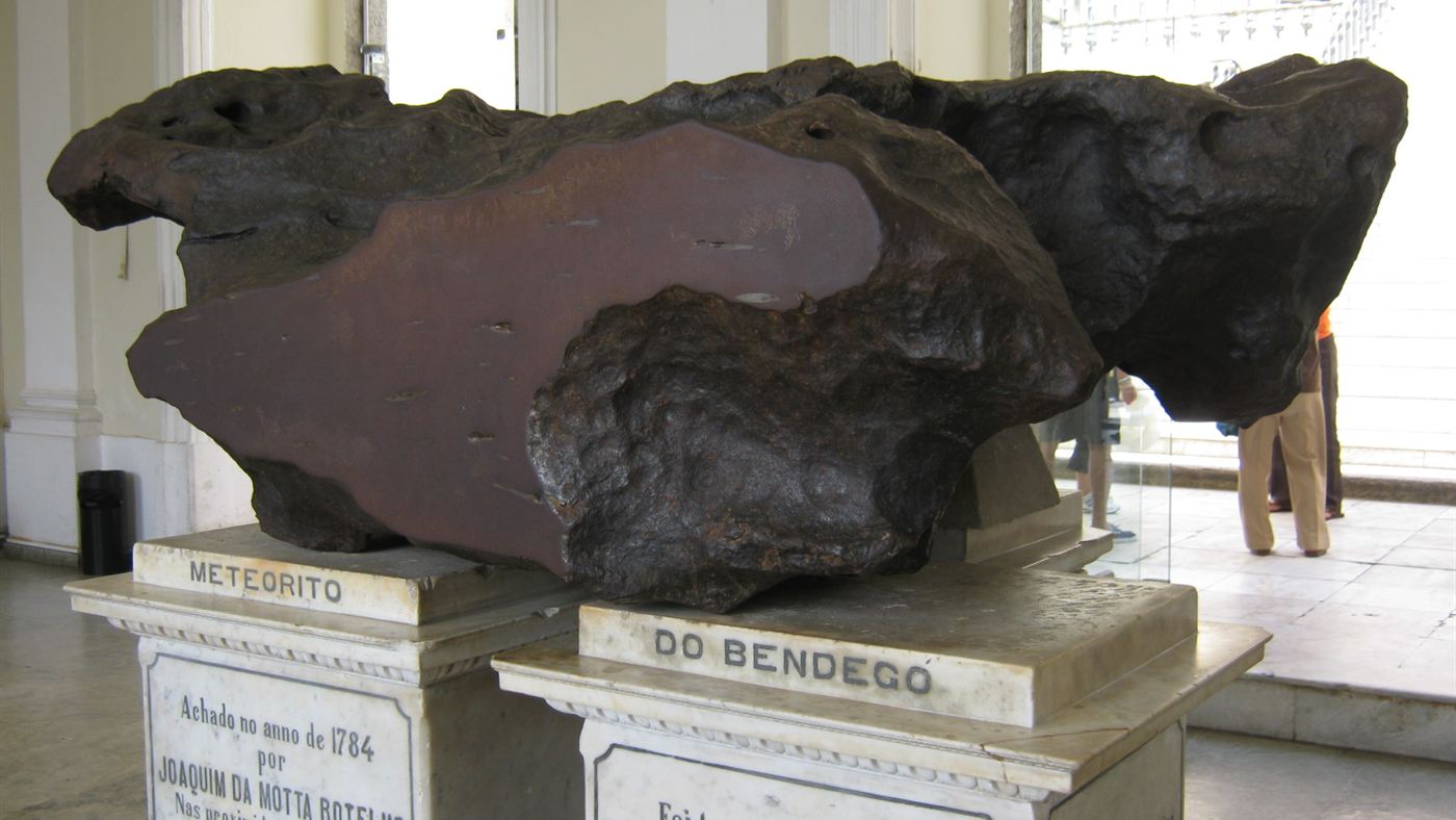 Meteorito de ferro do Bendegó, exposto sobre pedestal de mármore, com a placa que identifica a peça.