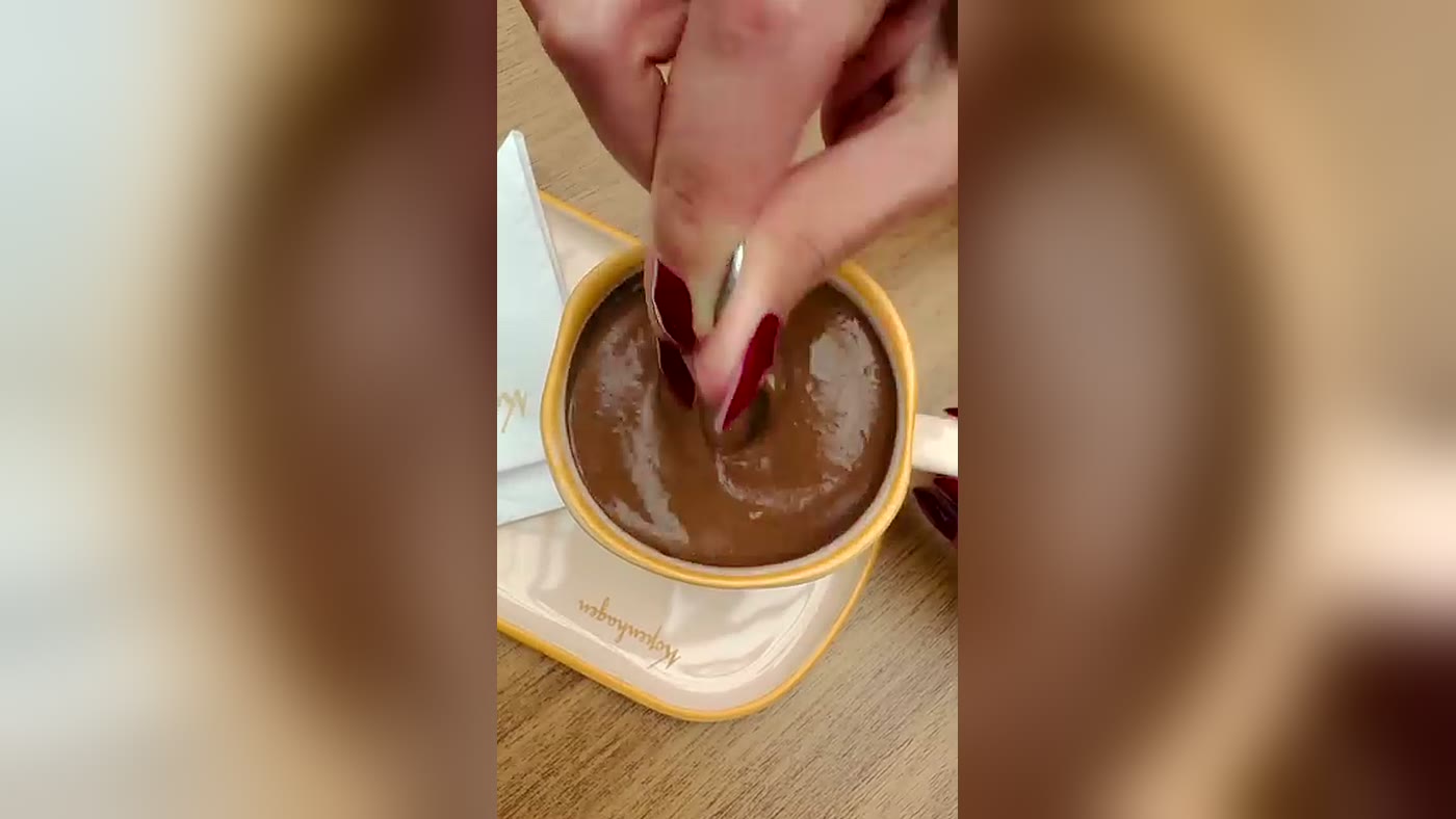 Cliente mexendo a xícara do Mexicano da Kopenhagen numa mesa de loja