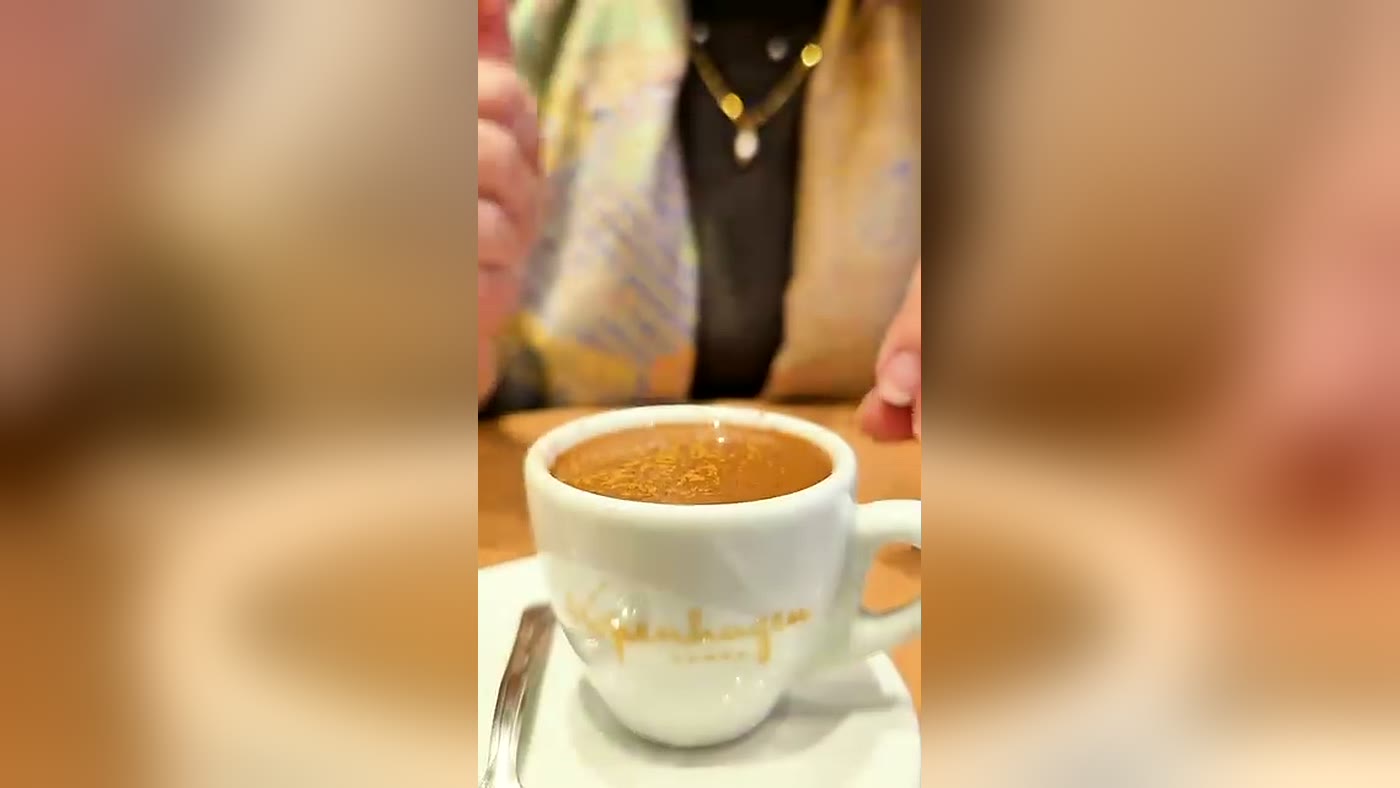 Cliente tomando o Mexicano da Kopenhagen numa xícara com o logo da marca
