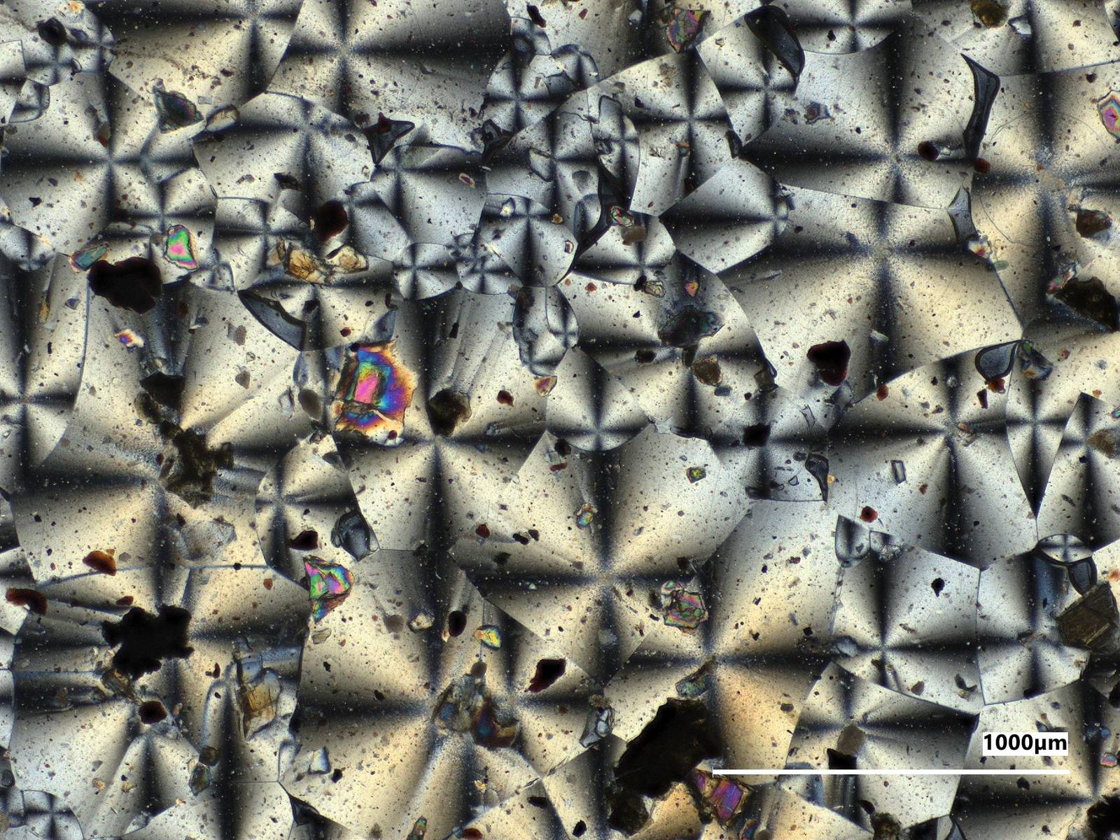 Vista no microscópio do material da NASA feito com poeira de Marte simulada: cristais em forma de estrela em tons de bege e cinza, com grãos escuros e avermelhados espalhados