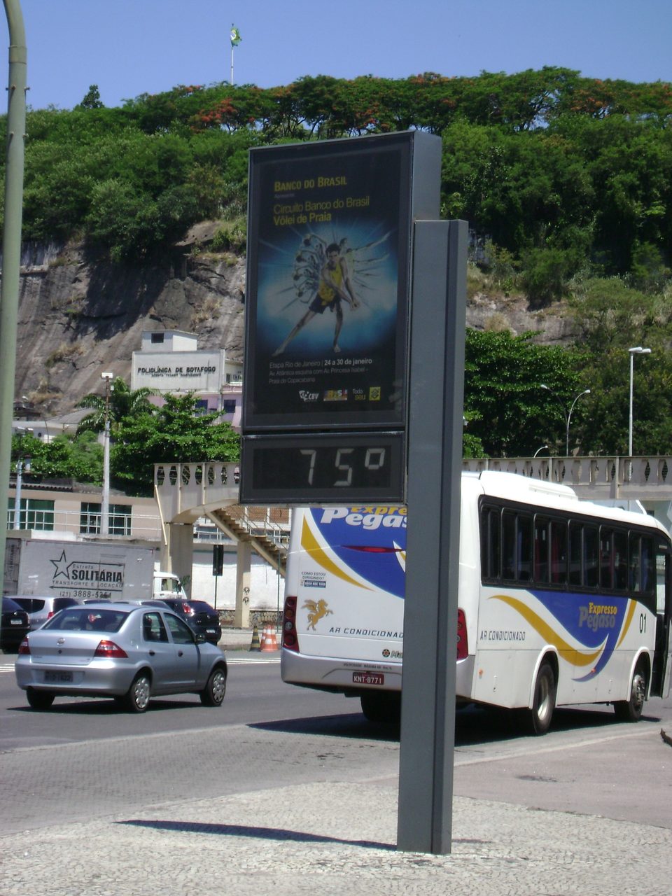 Termômetro digital de rua na praia de Botafogo, no Rio, mostrando 75 graus por erro, com um ônibus e carros passando
