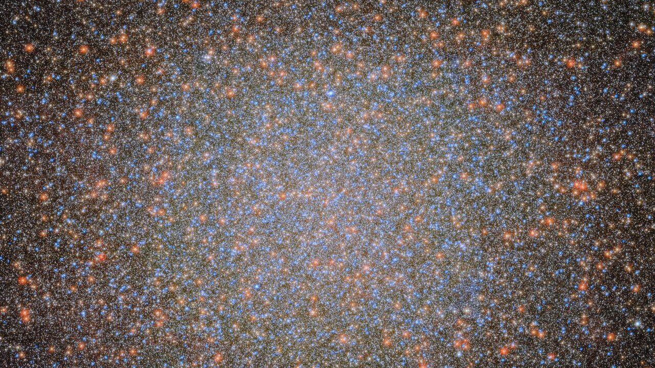 Aglomerado de estrelas Omega Centauri em imagem do Hubble, com milhares de estrelas azuis, brancas e alaranjadas concentradas no centro