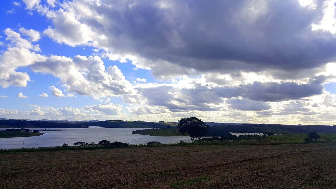 Represa de Jurumirim vista de uma área de lavoura, com árvores e céu com nuvens, no interior de São Paulo