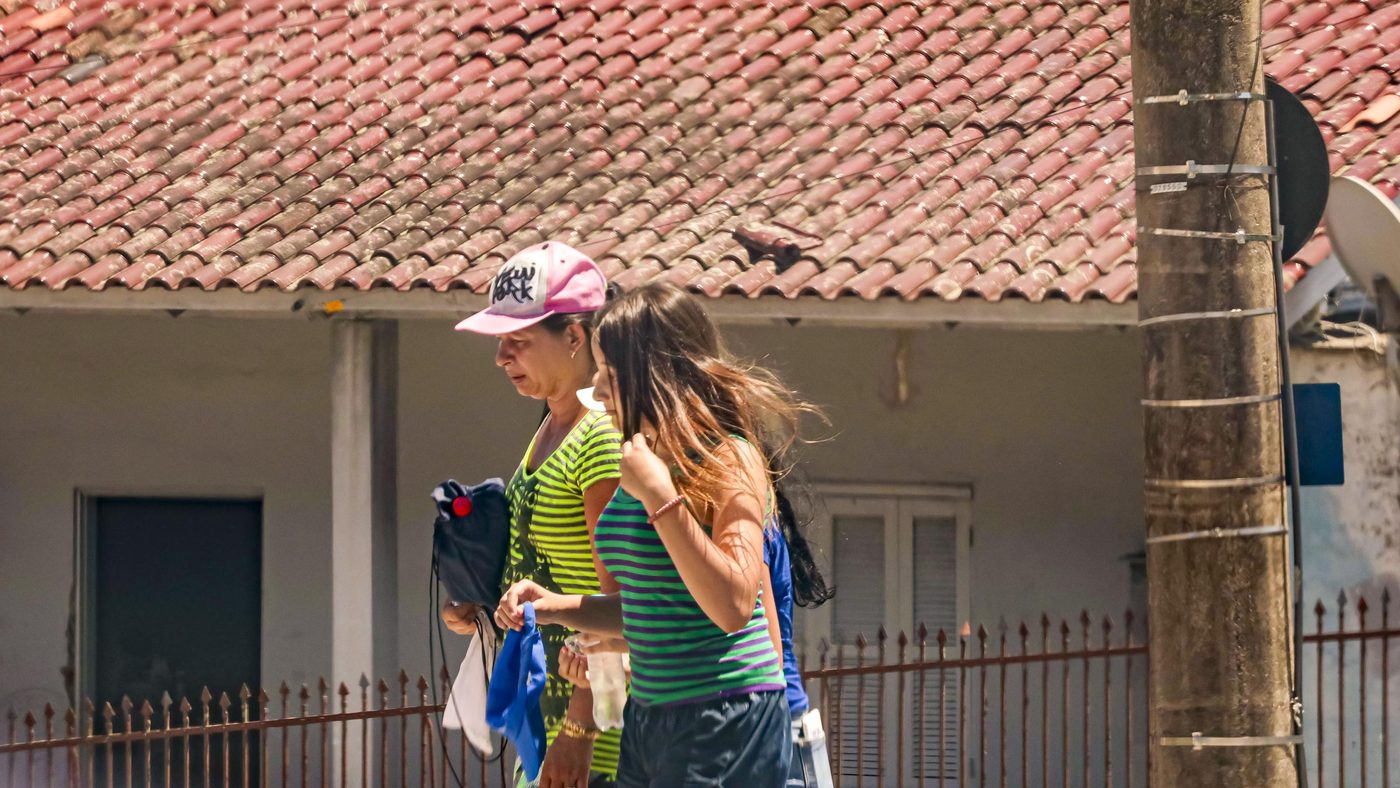 Moradoras caminham por rua de Porto Alegre (RS) sob sol forte durante onda de calor de fevereiro de 2025