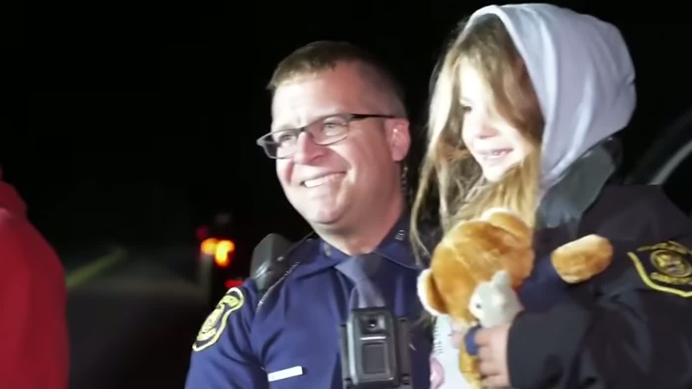 Policial sorri segurando Payton, a menina perdida na floresta encontrada a salvo com o cachorro
