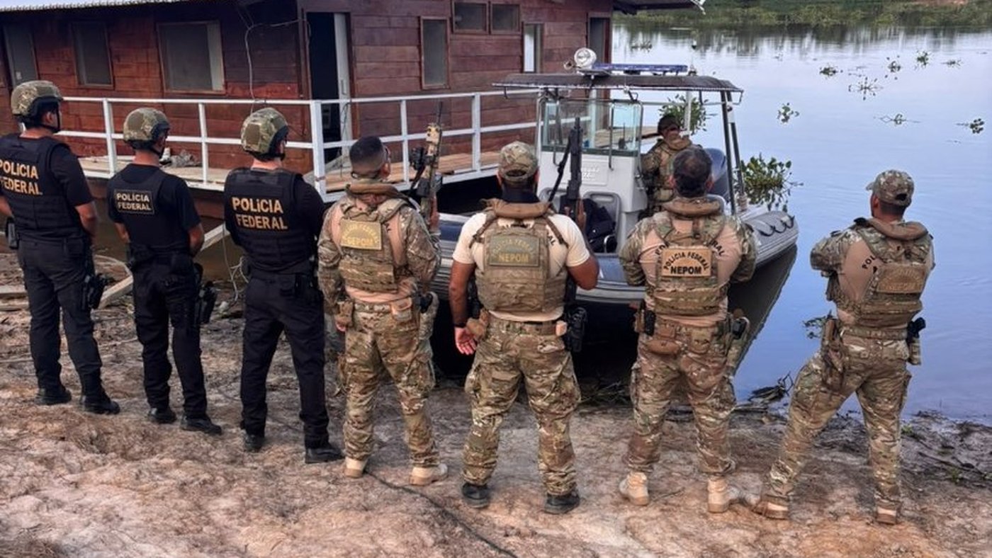 Policiais federais às margens de um rio no Pantanal, diante de uma casa flutuante e de uma lancha, na operação contra grilagem no Pantanal e incêndios