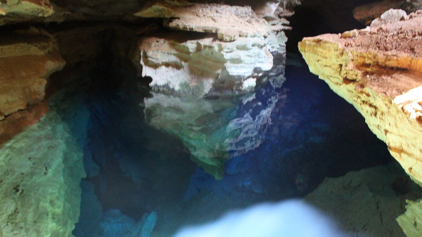 Água cristalina do Poço Encantado com reflexo azulado das paredes de rocha, na Chapada Diamantina