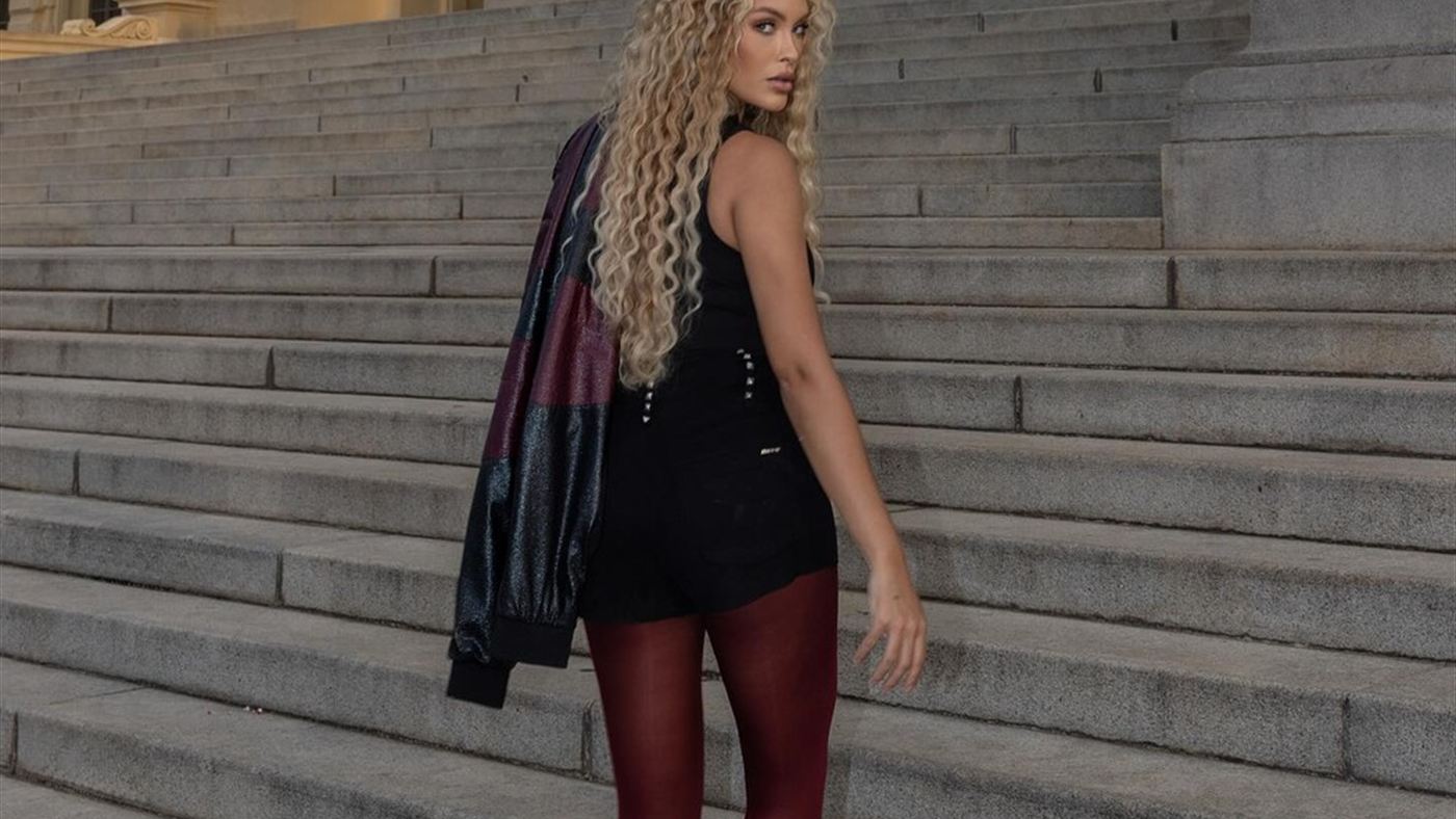 Sarah Andrade caminha em escadaria vestindo look preto e bordô em ensaio ao ar livre