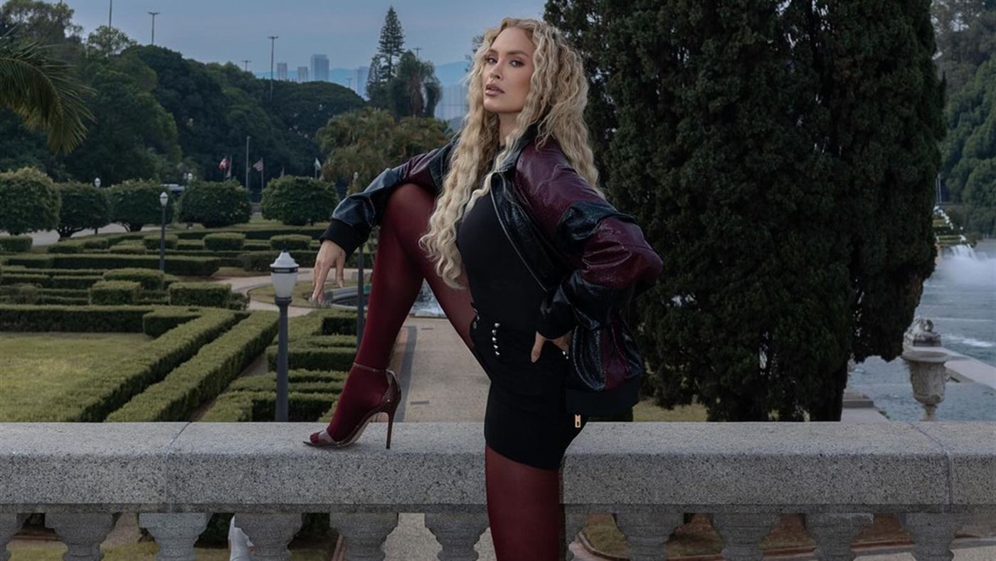 Sarah Andrade posa apoiada em um parapeito de pedra em jardim de São Paulo