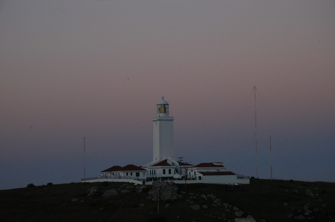 Farol de Santa Marta, branco, sobre um morro em Laguna, Santa Catarina, ao entardecer, no limite sul do defeso da sardinha-verdadeira