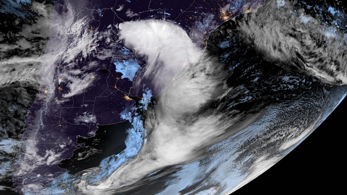 Imagem de satélite colorida da madrugada de 4 de outubro com a faixa de nuvens sobre o interior da América do Sul, o Sul do Brasil e o Atlântico