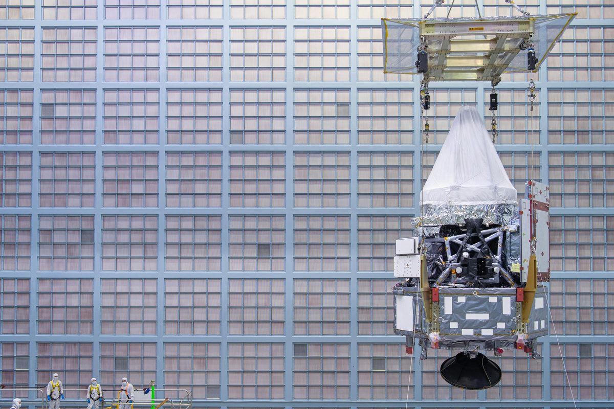 Corpo do telescópio Roman com os instrumentos, coberto por plástico, erguido por guindaste numa sala limpa do Goddard