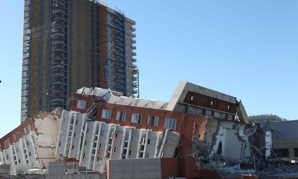 Prédio residencial alto tombado de lado e partido ao meio em Concepción, no Chile, com um edifício mais alto intacto ao fundo