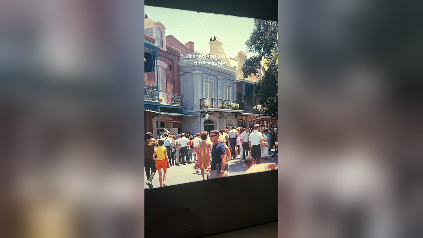 Homem de óculos escuros e camiseta justa em meio à multidão numa foto de 1968 da Disneylândia