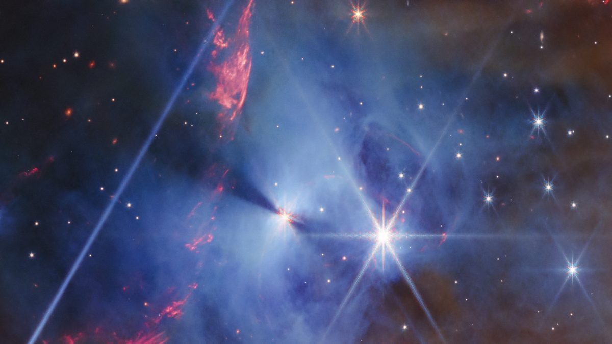 Nebulosa azul da NGC 7129 vista pelo Webb, com uma protoestrela no centro e a sombra de um disco em forma de rosca